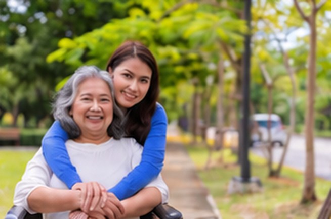 Senior woman embraced by her smiling daughter outdoors